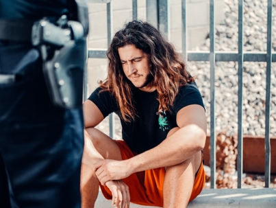 man sitting down arrested in front of police officer